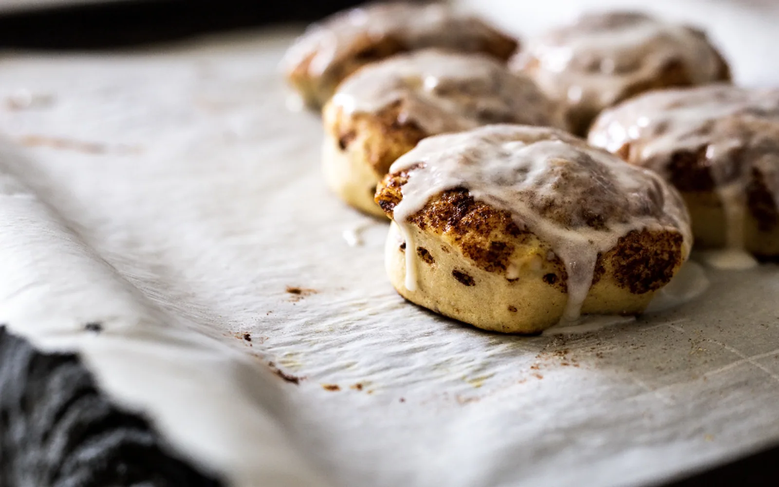 Cinnamon rolls drizzled with white icing on baking paper