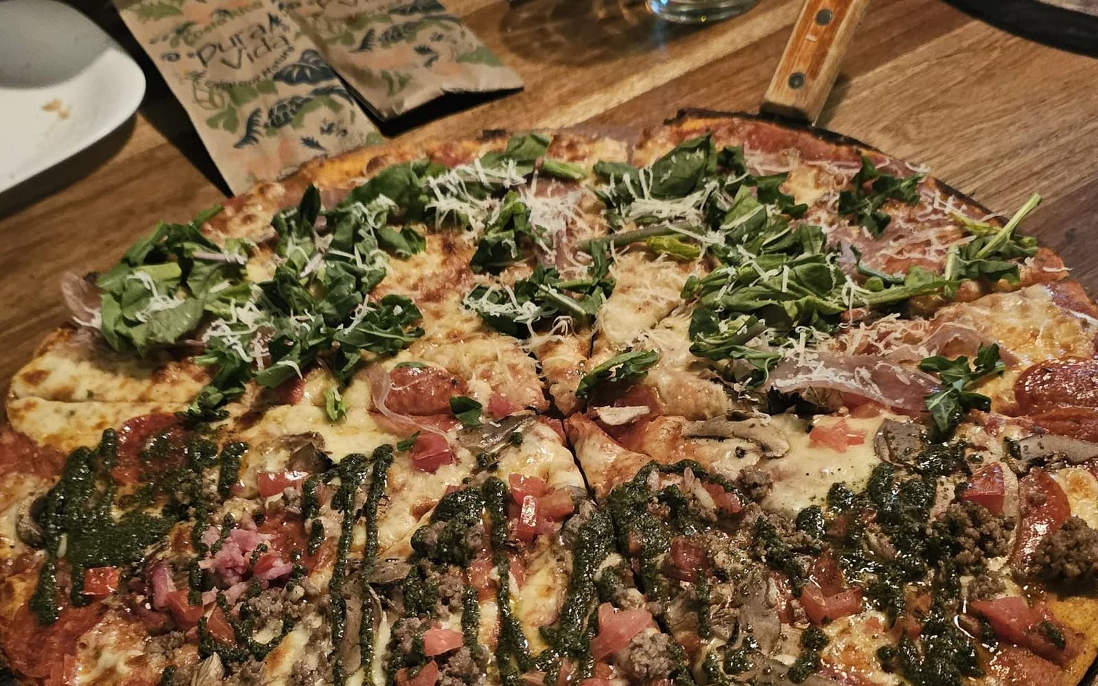 Meat-topped pizza with cured sausage and rocket, cut into slices