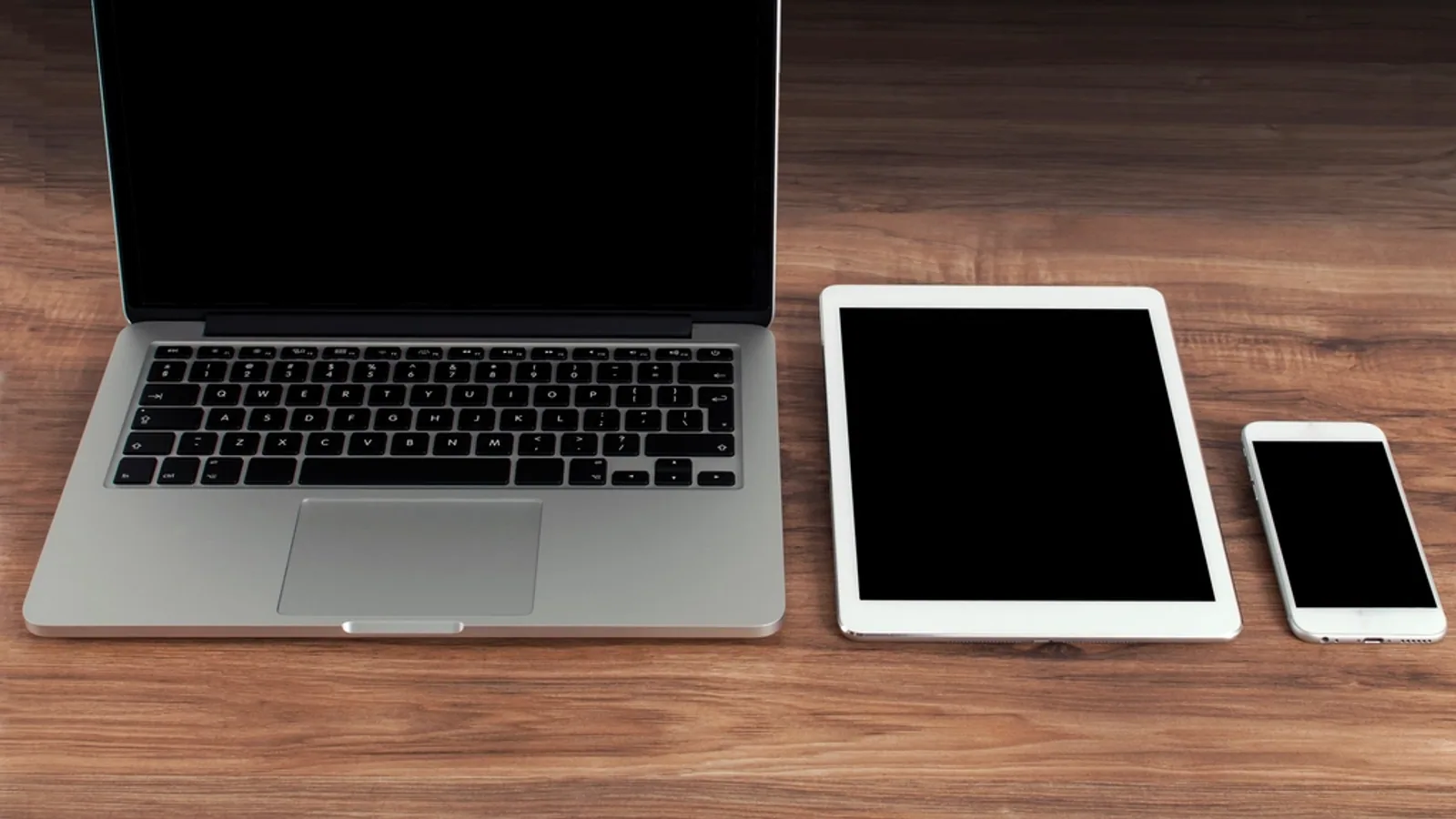 A laptop, tablet and phone laid out on a desk