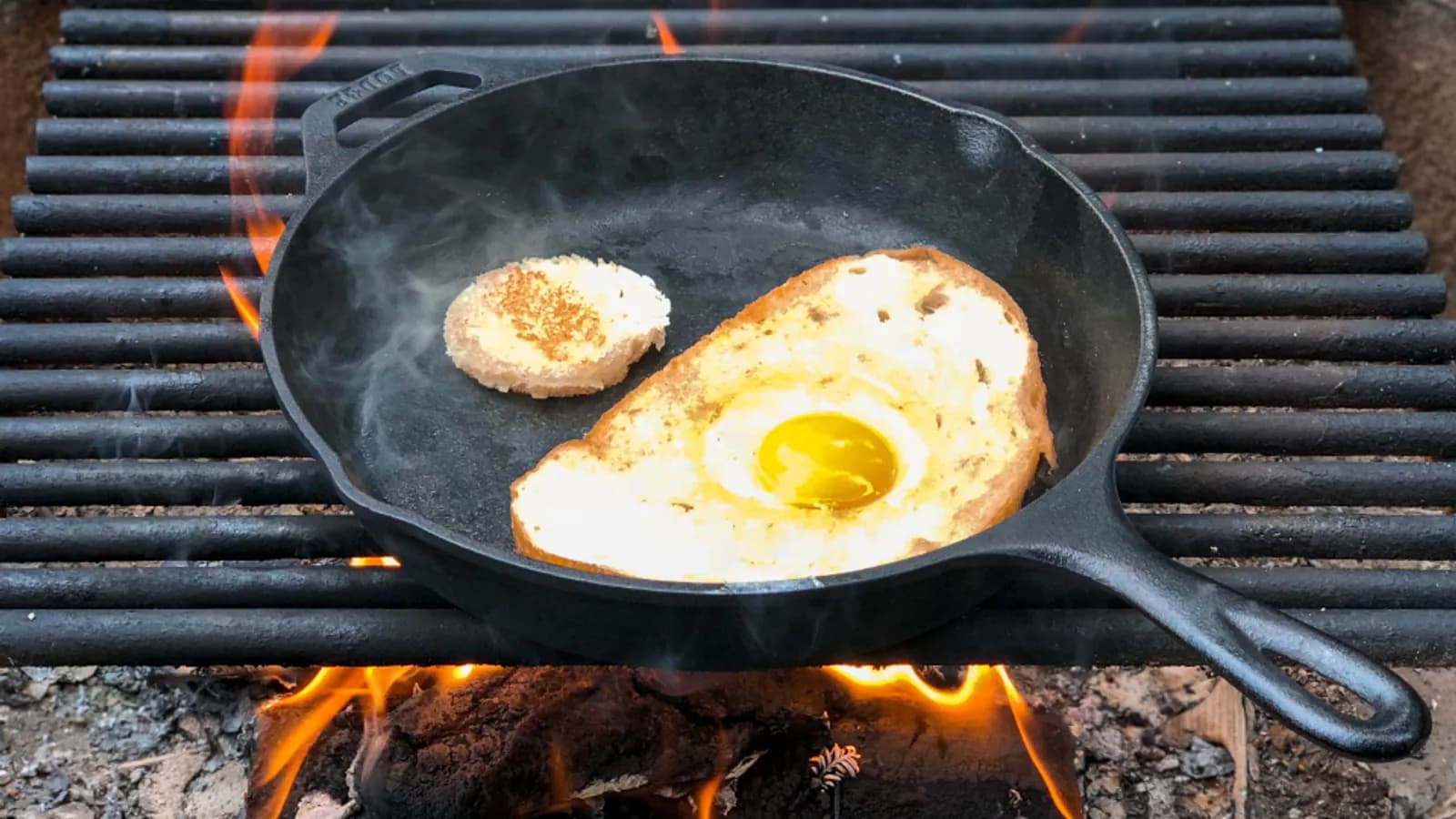 A cast iron skillet cooking over an open flame